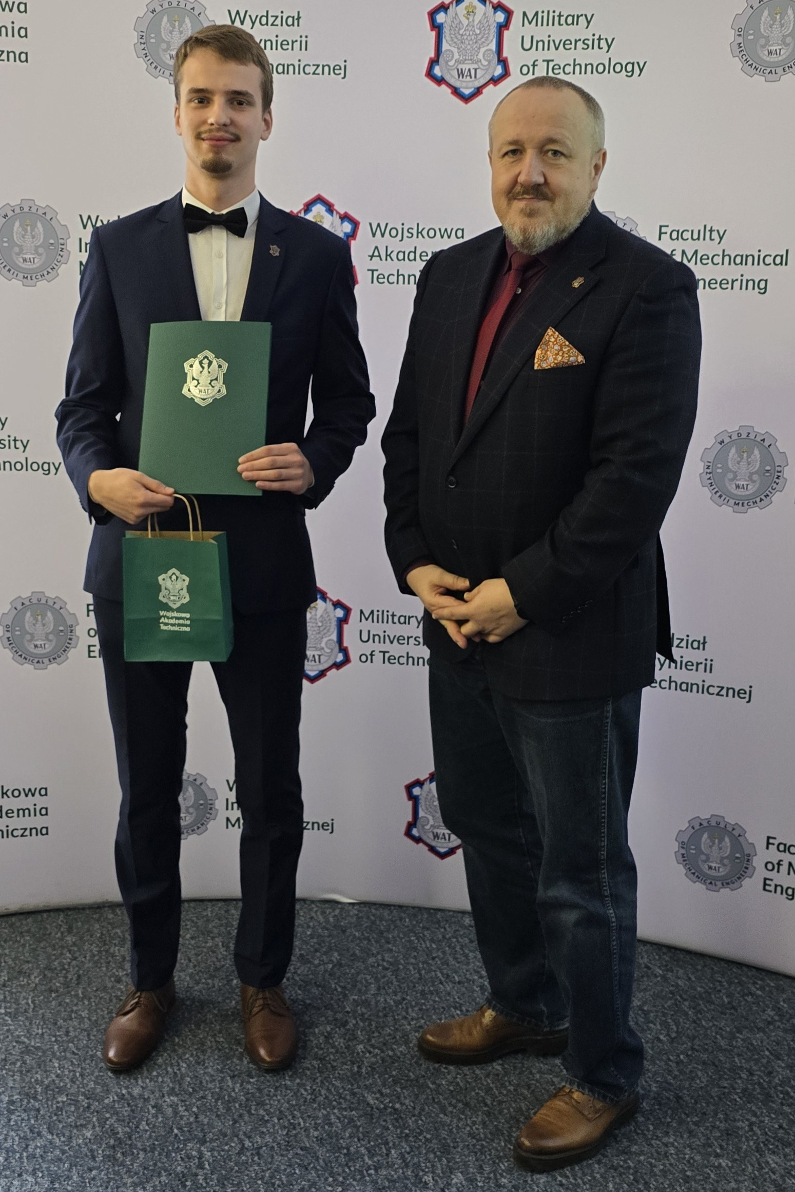 Fot. 2. Michał Żaba i dziekan Jerzy Małachowski na tle ścianki wydziałowej z logiem WIM WAT.
